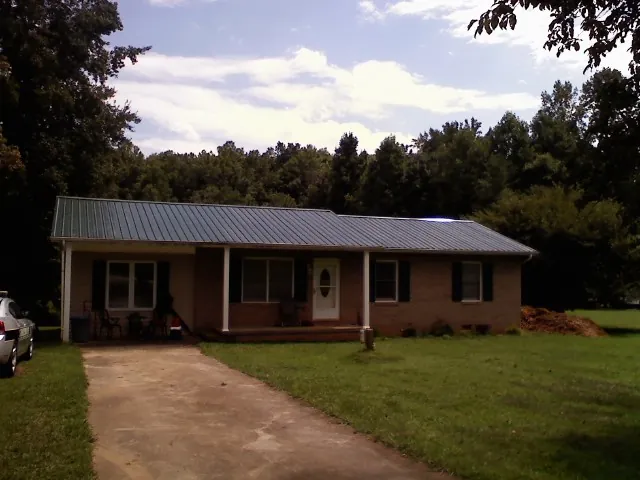 Dark green metal roof on a brick ranch with a covered porch in Callaway